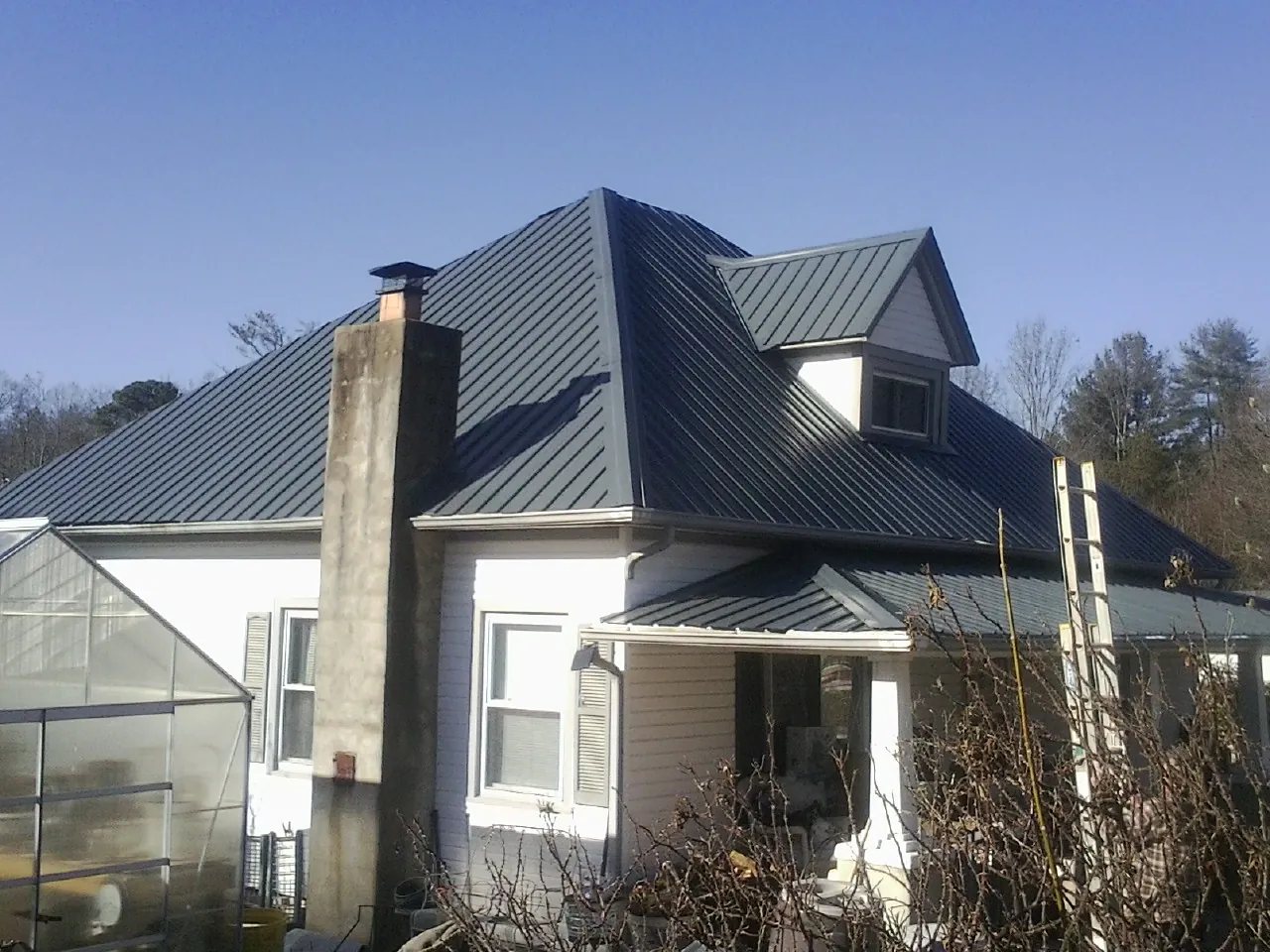 Dark blue standing seam metal roof on a white farmhouse with dormer — Slate & Tile Roof Repair by Roofing Brothers in Scotia