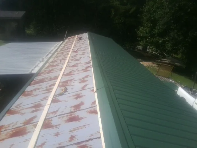 Old rusted panels beside newly installed green metal roofing — Wind Damage Roof Repair by Roofing Brothers in Scotia