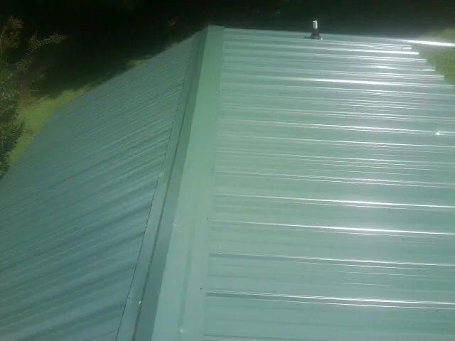 New green metal panels meeting at the ridge of a roof — Flat Roof Repair work by our crew in Scotia