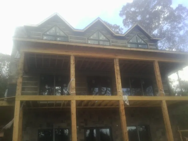 Dormers and porch framing on a large log home under construction — Roof Coating work by our crew in Scotia