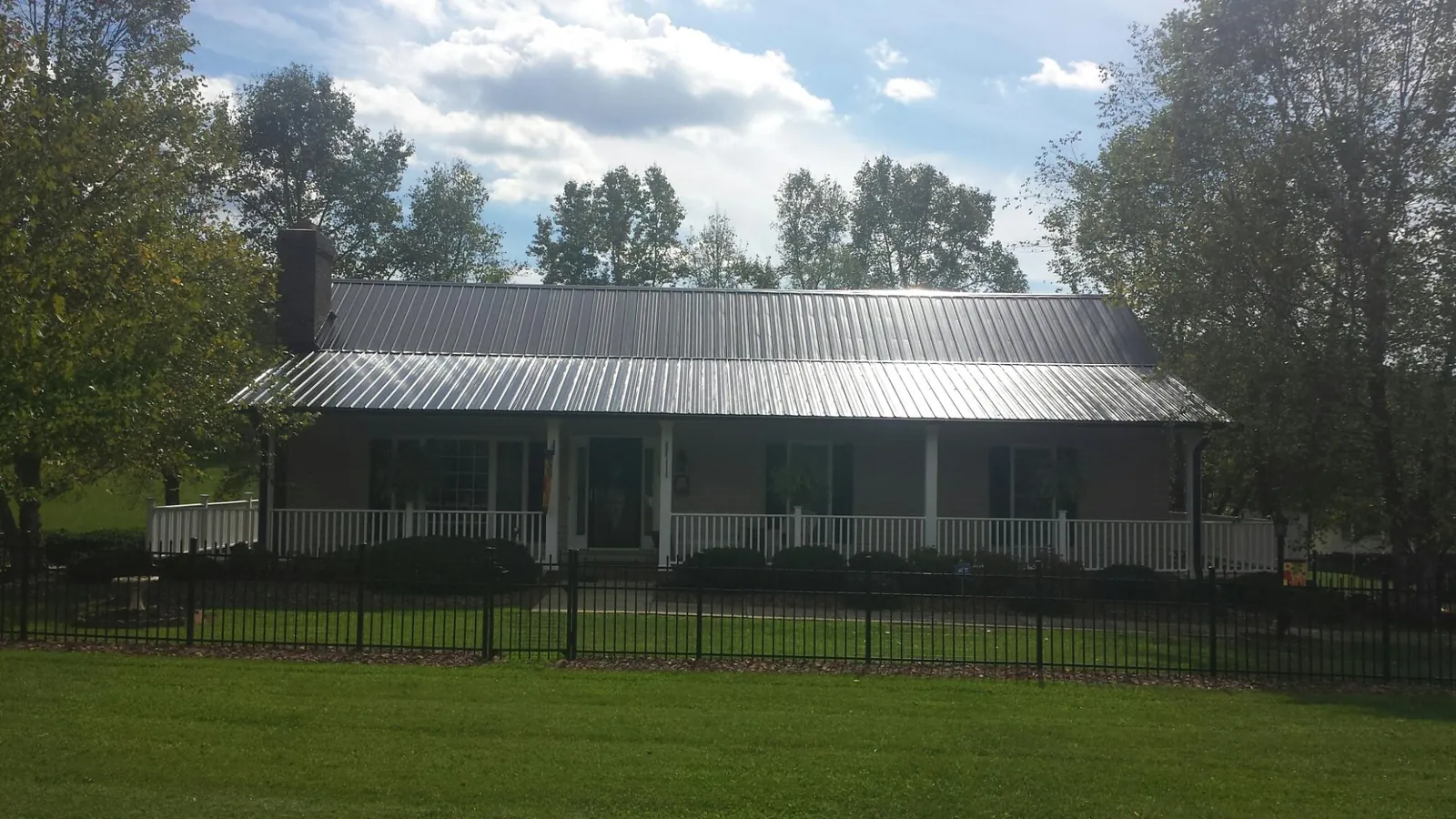 Gray metal roof on a brick ranch with a full width front porch — Gutter Guard Installation work by our crew in Scotia
