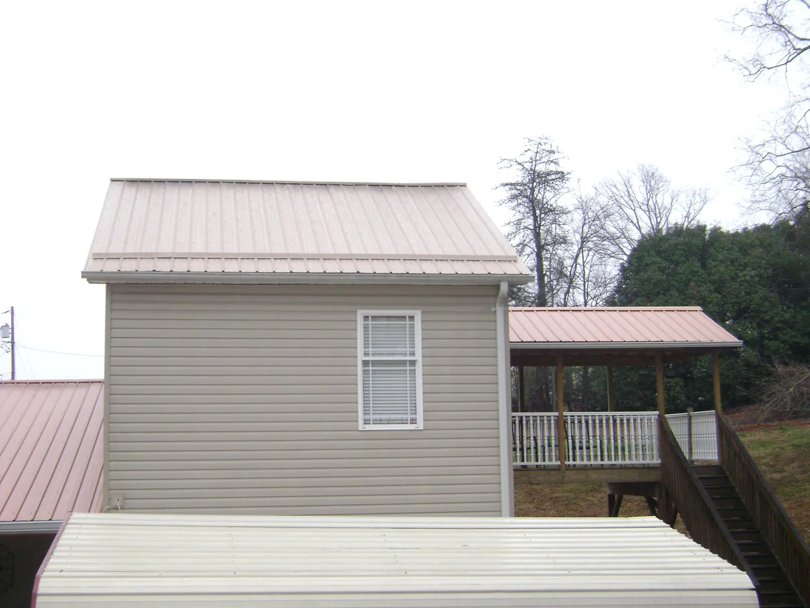 Tan metal roofs on a two story addition and attached porch, from a Roof Replacement job in Scotia